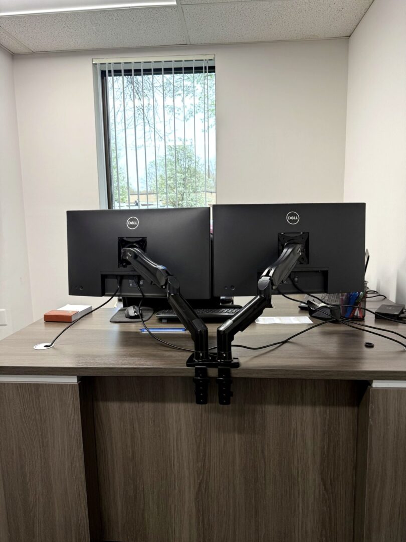 Dual Dell monitors on articulating arms installed at commercial office workstation by Secur3iT