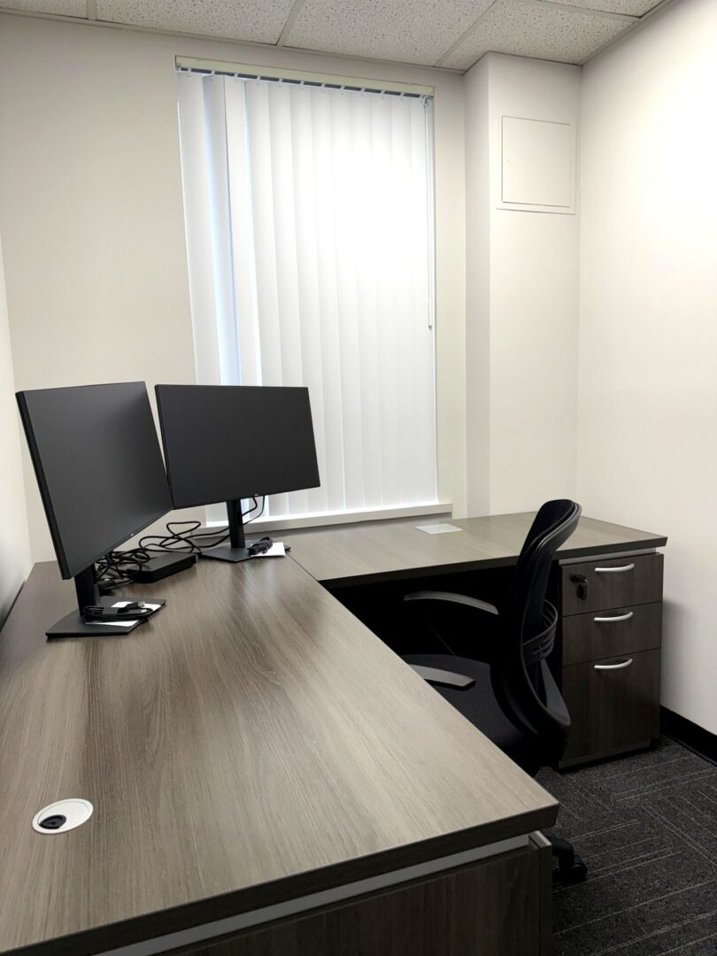 L-shaped office desk with dual monitor setup deployed by Secur3iT for commercial client